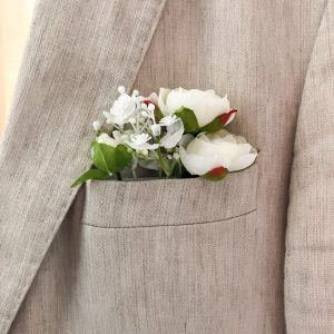 Pochetcorsage met witte bloem in borstzak van bruidegom.